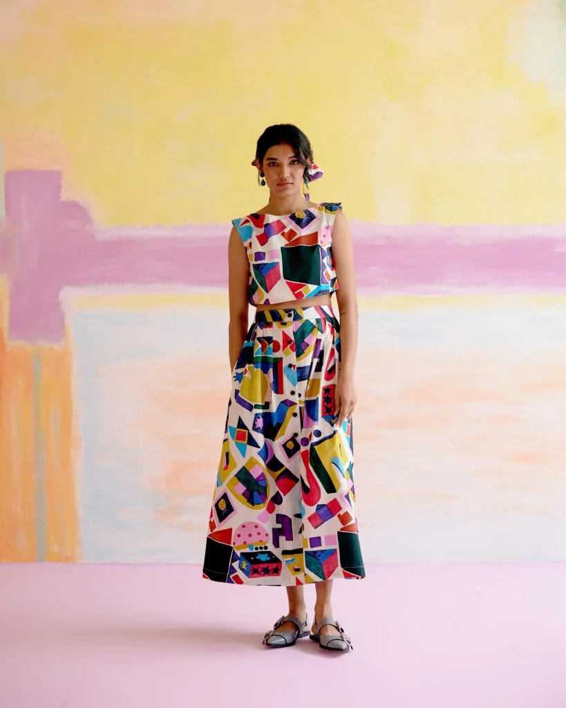 The image displays a woman wearing an artistic co-ord set with Arcade Print featuring a sleeveless boxy top and a matching vintage-inspired skirt. Copyright Happï Space.