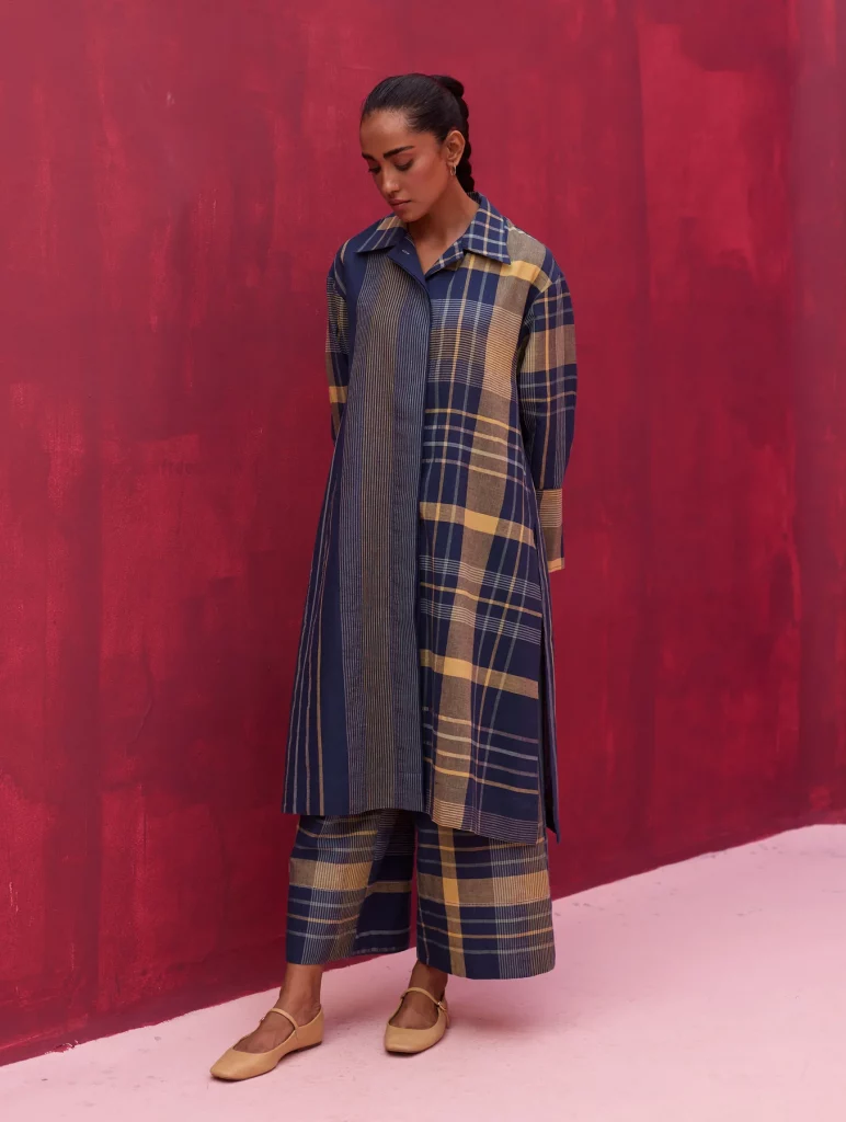The image displays a woman wearing a checkered linen shirt kurta in navy blue. Copyright Manan.
