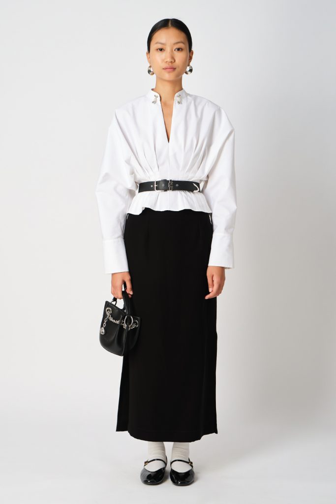 The image displays a woman wearing a white shirt with silver fringe detailing and dolman sleeves, as well as a black maxi skirt. Copyright moonray.