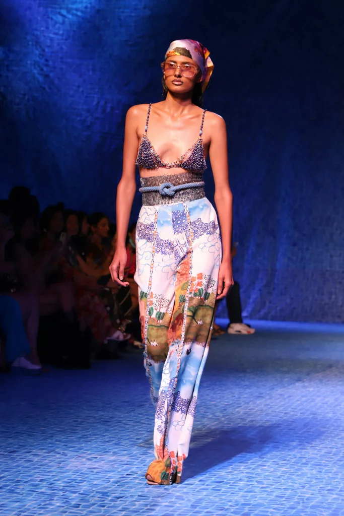 The image displays a woman wearing a sparkly bustier, wide-leg pants with a pattern, sunglasses, and head scarf. Copyright Rajesh Kumar Verma/Pexels.