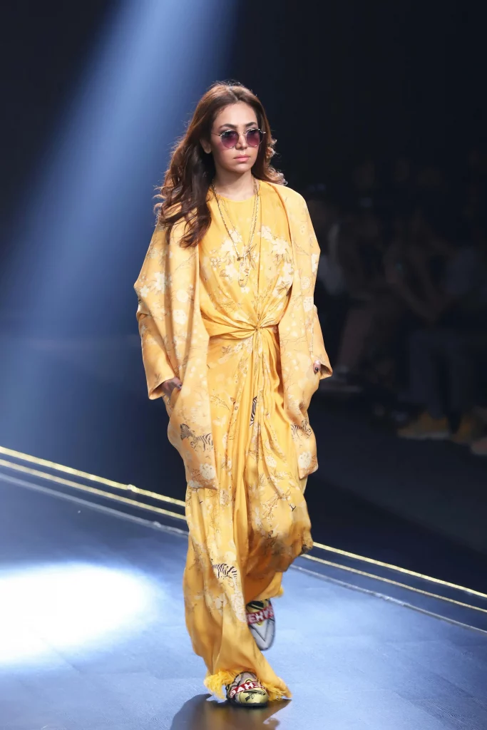 The image displays a woman wearing a jumpsuit, jacket, mules, sunglasses, and jewelry. Copyright Rajesh Kumar Verma/Pexels.