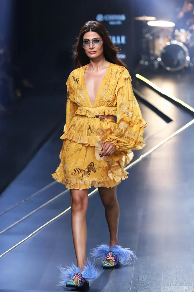 The image displays a woman wearing a ruffle top, a ruffle skirt, mules, and sunglasses. Copyright Rajesh Kumar Verma/Pexels.