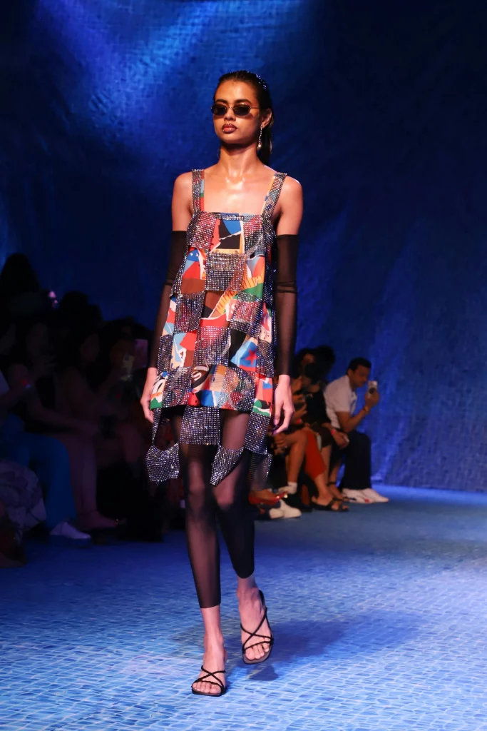 The image displays a woman wearing a sparkly mini dress, sheer leggings, strappy heels, sunglasses, and jewelry. Copyright Rajesh Kumar Verma/Pexels.
